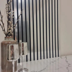 Decorative setting with a vase, glasses, and striped wallpaper.