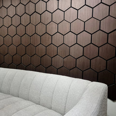 Hexagonal wooden panel wall with a gray sofa in front