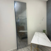 Tall vertical mirror with black slats in a modern interior setting.