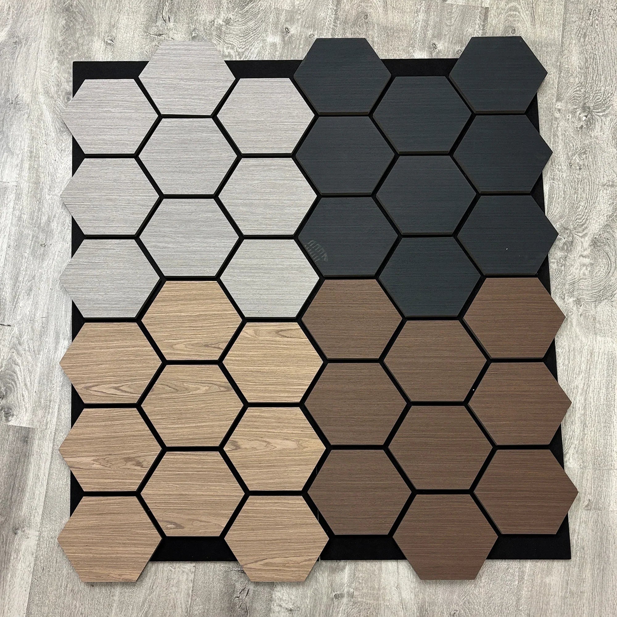 Hexagonal tiles in black, gray, beige, and brown on a wooden floor.